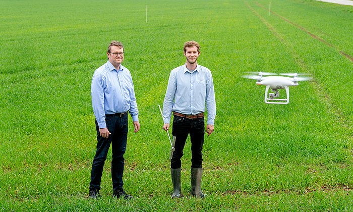 Prof. Heinz Bernhardt, Lehrstuhl für Agrarsystemtechnik, und sein Mitarbeiter Andreas Schweiger stehen auf dem Versuchsfeld mit Drohne.