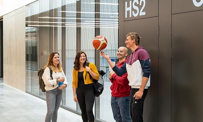 Students stand in a group and play with a ball