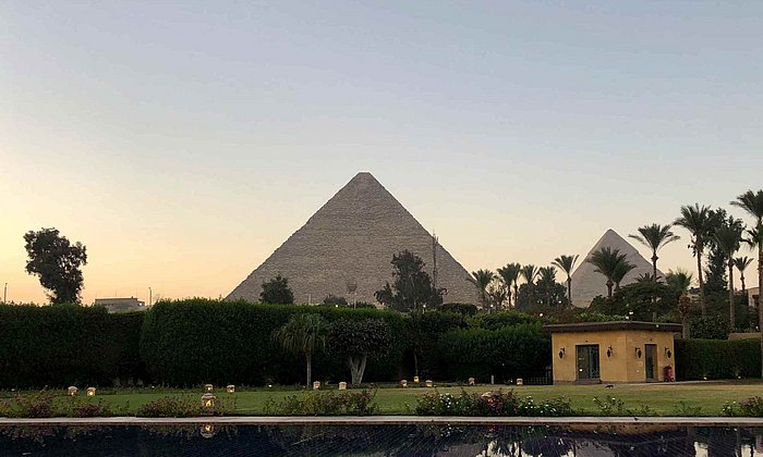 Cheops-Pyramide aus der Entfernung, im Vordergrund Palmen und Wasser