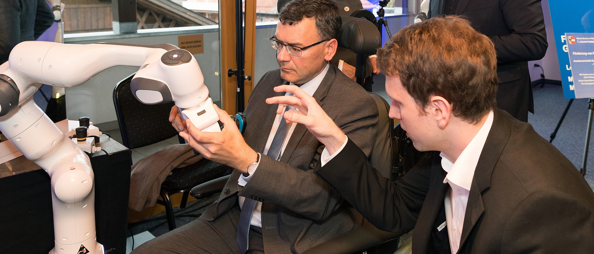 Bei der Eröffnung erprobt Staatsminister Dr. Florian Hermann einen Rasier-Roboter. Im Hintergrund unterhalten sich Garmisch-Partenkirchens 1. Bürgermeisterin Dr. Sigrid Meierhofer und Prof. Sami Haddadin.