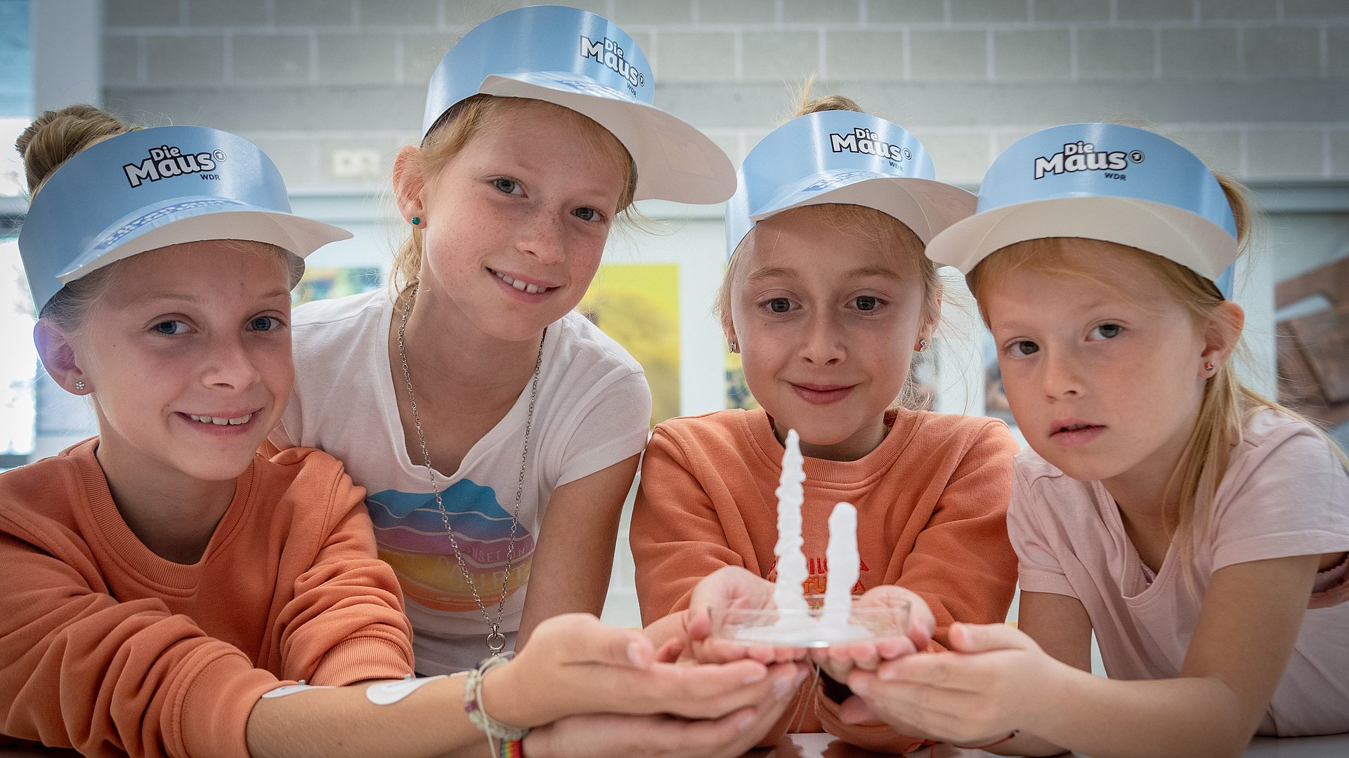 Four girls with Die-Maus caps holding a petri dish.