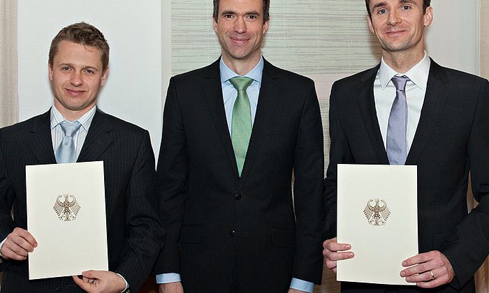 Stefan Müller (Mitte), Parlamentarischer Staatssekretär im Bundesministerium für Bildung und Forschung, übergibt Dr. Tobias Haack (links) und Dr. Julien Gagneur (rechts) eine Förderurkunde für ihr Projekt "mitOmics". (Foto: U. Benz / TUM)