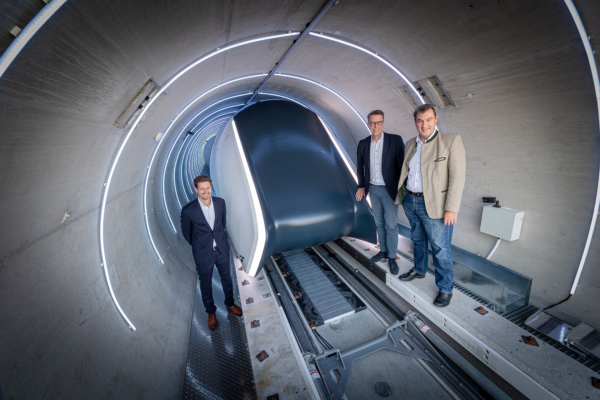 Three people stand around the Hyperloop Pod in the tube.