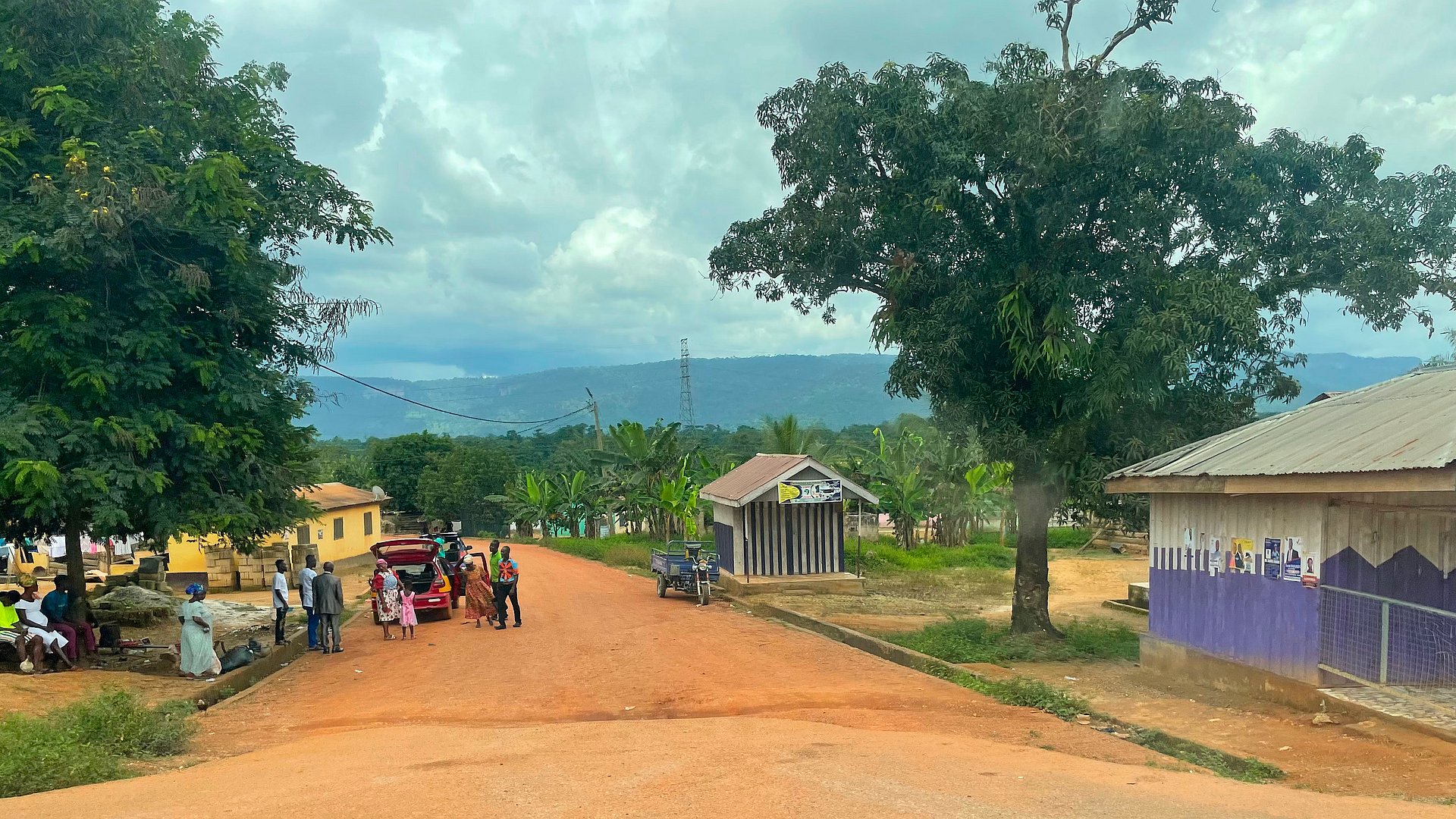 A rural road in Ghana with houses and people