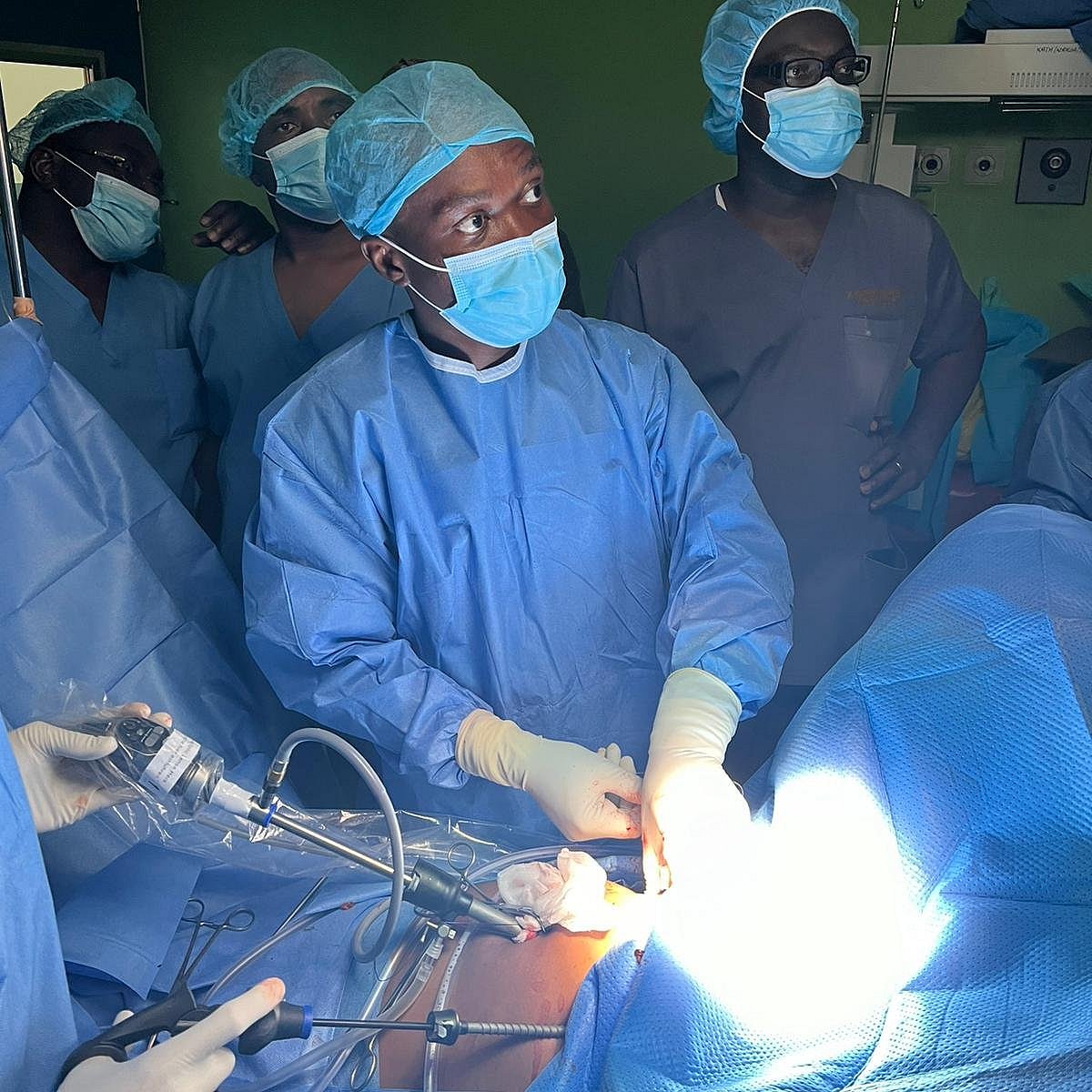Surgical team operating with instruments on the covered abdomen