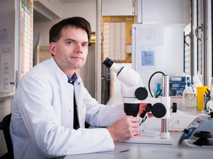 Professor Thomas Korn sitting in front of a microscope .