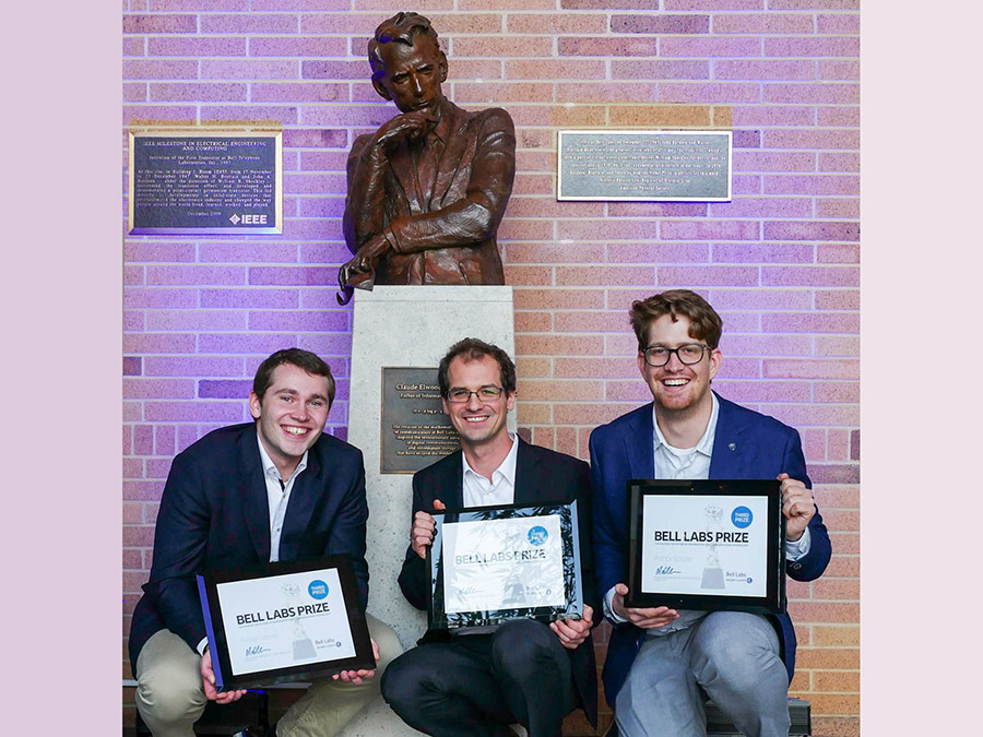 TUM-Forscher Fabian Steiner, Georg Böcherer, und Patrick Schulte (vlnr) vor der Statue von Claude Shannon, Vater der Informationstheorie.