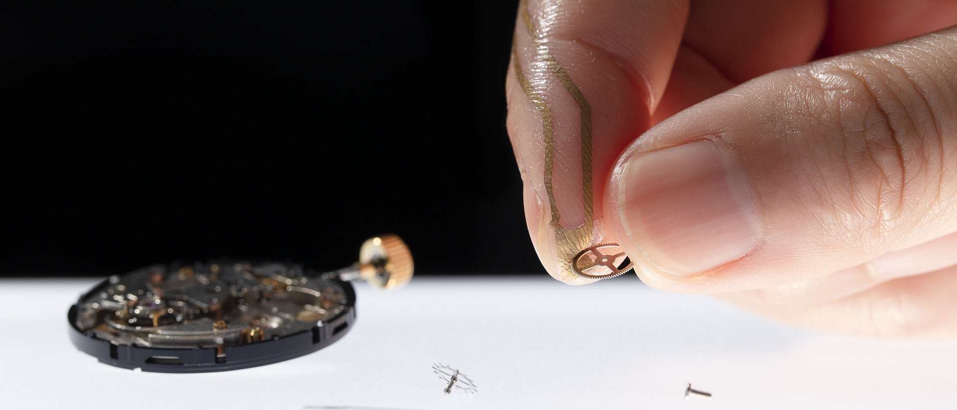 Two fingers are holding a small piece of metall. One finger is equipped with the nanomesh sensor.