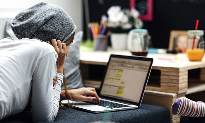 Jugendliche liegt mit Laptop auf einem Sofa.  (Bild: vgajic / istockphoto.com)