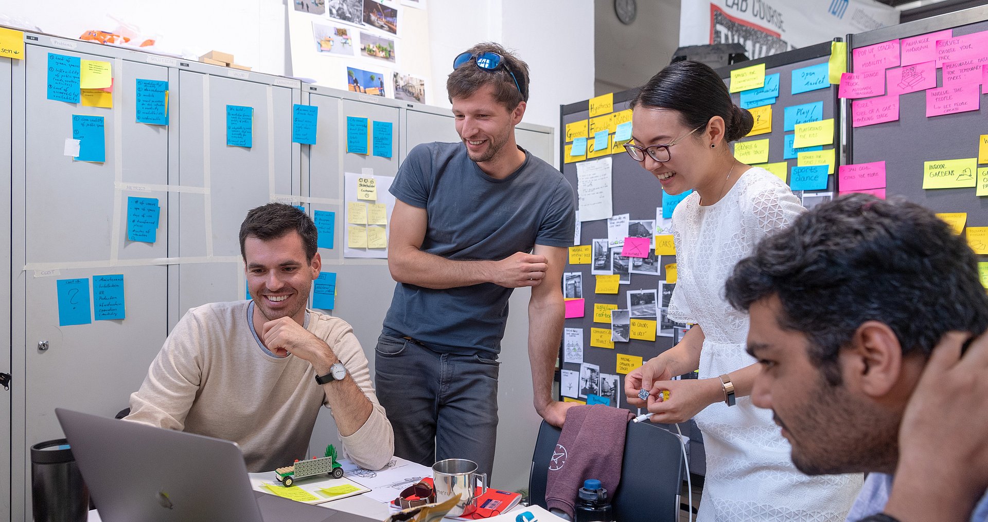 Makeathon Think.Make.Start an der TUM Vier Teilnehmende des Makeathons Think.Make.Start an der TUM besprechen sich. Im Hintergrund sind Whiteboards mit Post-its zu sehen.