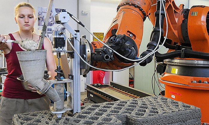 At the pilot plant for additive manufacturing, a multi-functional wall element is produced. Bachelor student Bettina Saile fills the test extruder with fresh concrete.