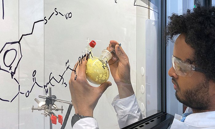 Dawit T. Filmon, Mitarbeiter von Prof. Nicolas Plumere, Professur für Elektrobiotechnologie am TUM Campus Straubing für Biotechnologie und Nachhaltigkeit, hält einen Ausgangsstoff für die Seitenketten des schützenden Polymers in seinen Händen.