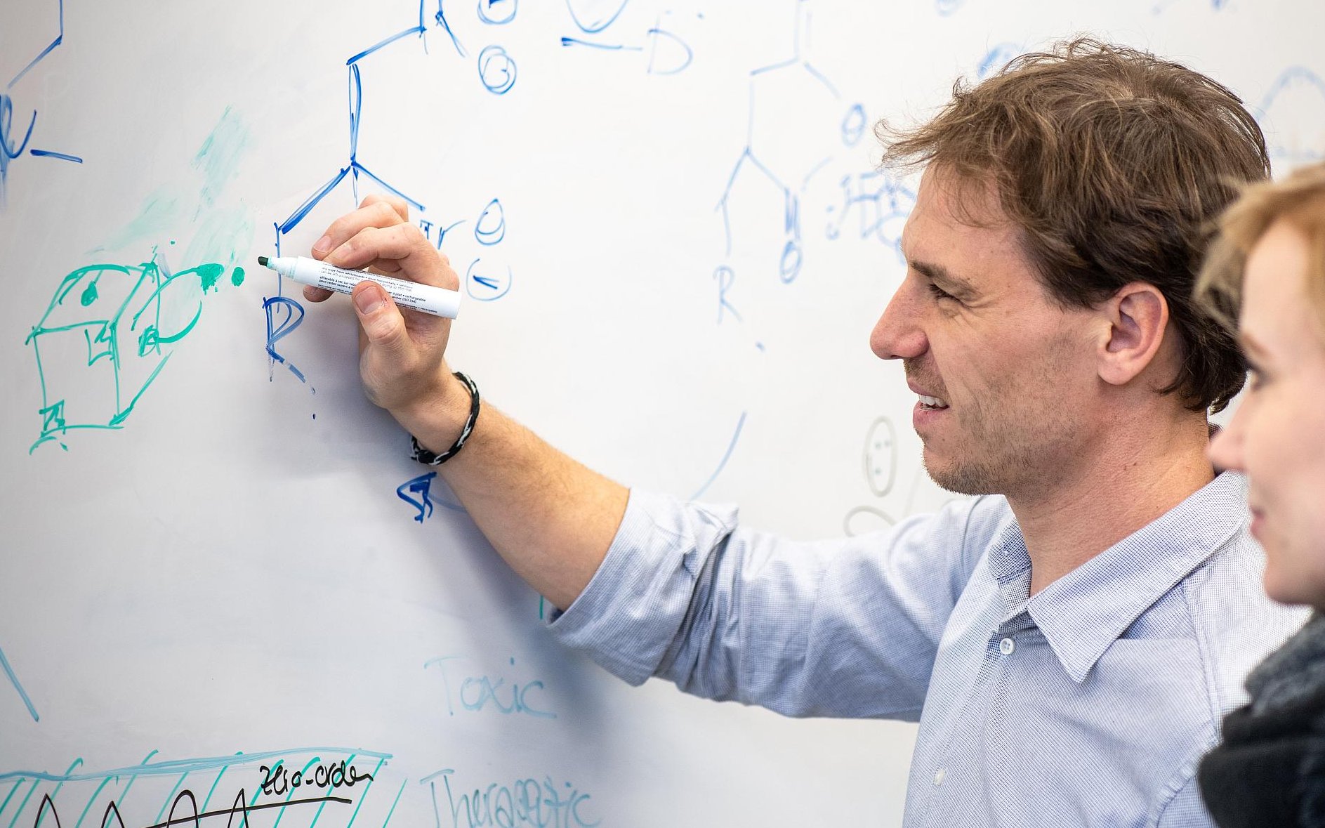 Prof. Job Boekhoven (l.) schreibt Strukturformeln an einem Whiteboard