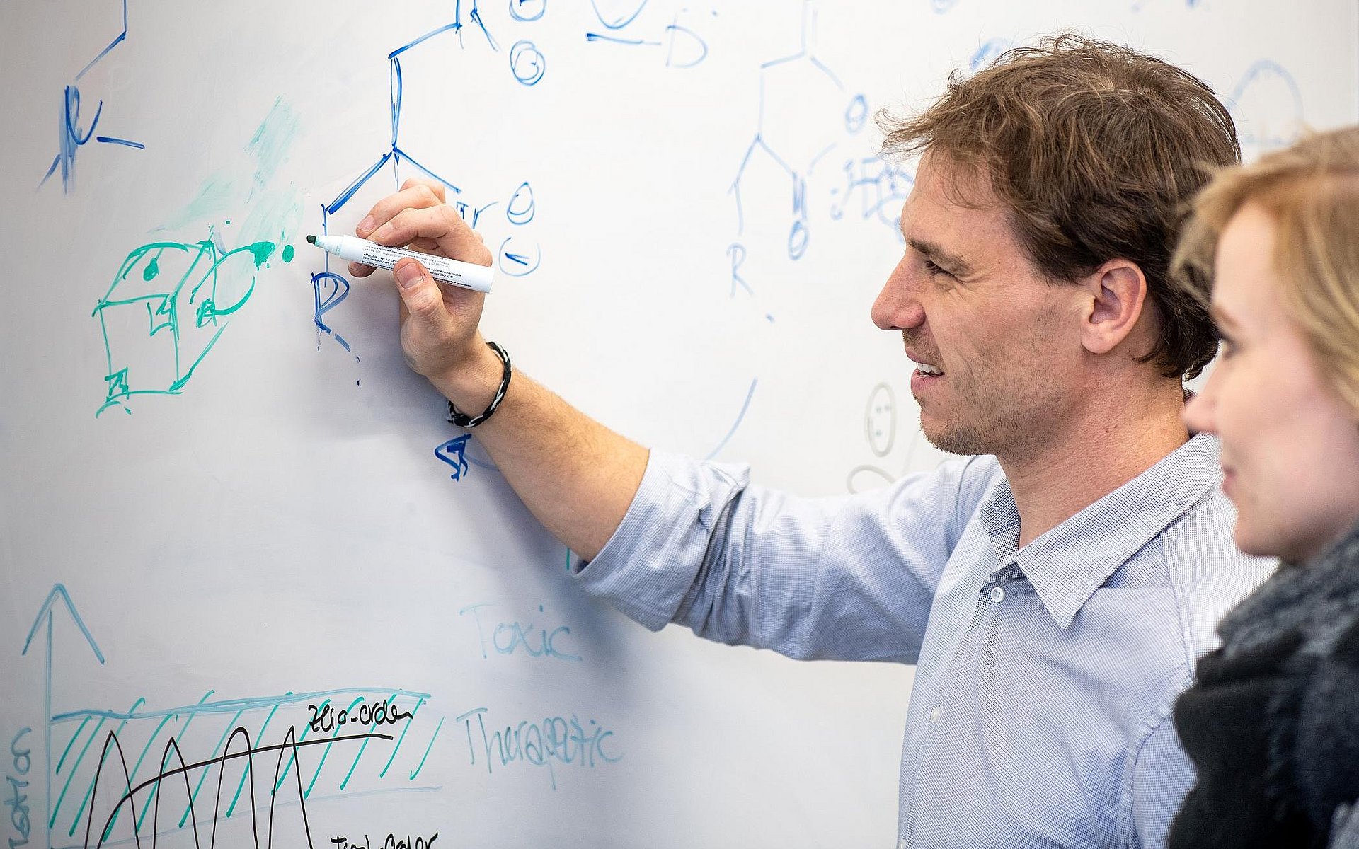 Prof. Job Boekhoven (l.) schreibt Strukturformeln an einem Whiteboard