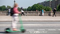 Ein Mensch fährt mit einem E-Scooter über eine Brücke