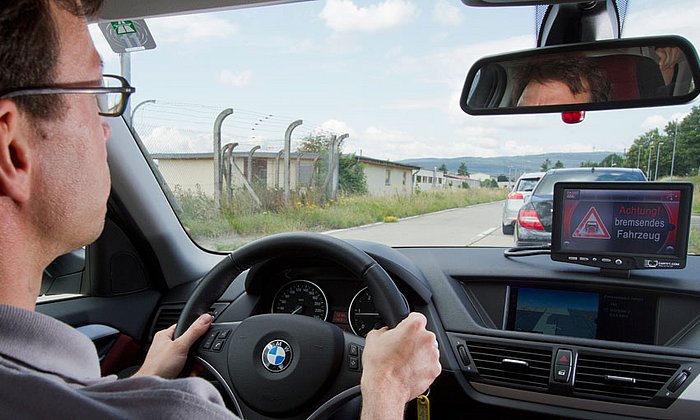 Noch bevor der Fahrer die Vollbremsung des vorausfahrenden Autos wahrnehmen kann, wird er vom simTD-System gewarnt. (Bild simTD)