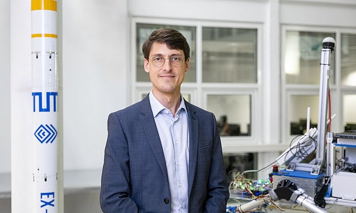 Portrait von Prof. Philipp Reiss neben einem Raketenmodell