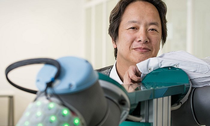 TUM-Prof. Gordon Cheng neben einer seiner Robotik-Kreationen: Ein Roboterarm mit der von Cheng entwickelten künstlichen Haut.