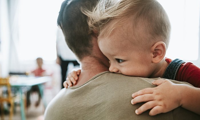 Ein Kleinkind auf dem Arm eines Erwachsenen