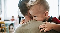 Ein Kleinkind auf dem Arm eines Erwachsenen