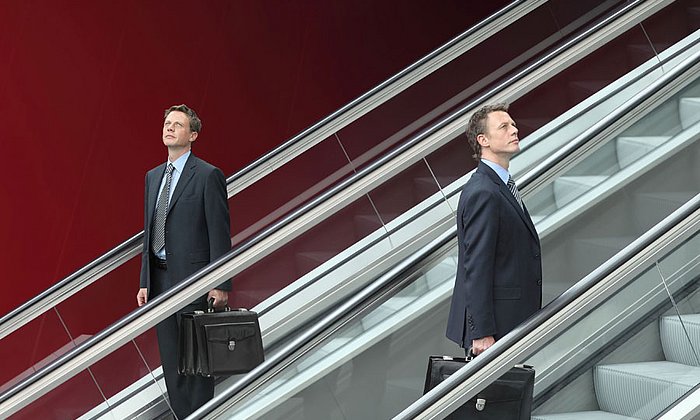 Men in suits on escalators in opposite directions