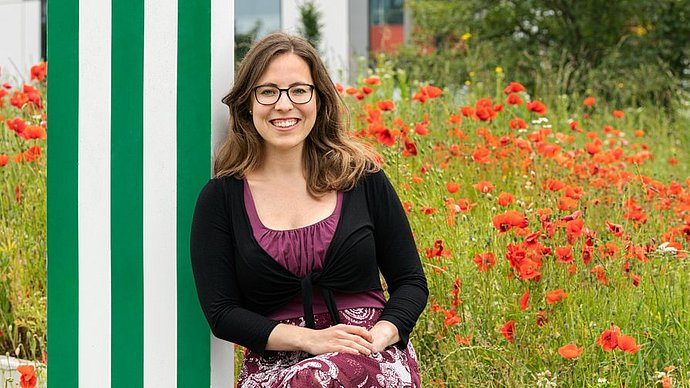 Michaela Wilfling in front of a field with poppies 