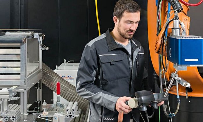 André Heckert, wissenschaftlicher Mitarbeiter am iwb, positioniert den Laser für die Bearbeitung des Metalls für das Fügen von Metall- Kunststoff-Verbindungen.