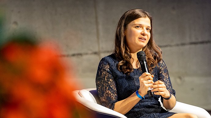 Die ehemalige Stipendiatin Bianca Monzer spricht mit Mikrofon in der Hand auf dem Podium der Festveranstaltung des Deutschlandstipendiums.