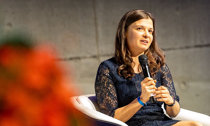 Die ehemalige Stipendiatin Bianca Monzer spricht mit Mikrofon in der Hand auf dem Podium der Festveranstaltung des Deutschlandstipendiums.