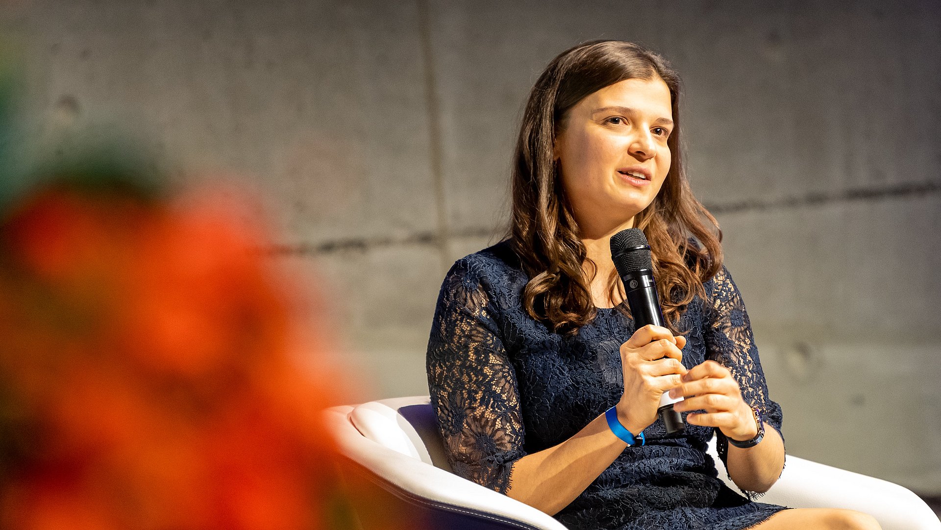 Die ehemalige Stipendiatin Bianca Monzer bei der Festveranstaltung des Deutschlandstipendiums Die ehemalige Stipendiatin Bianca Monzer spricht mit Mikrofon in der Hand auf dem Podium der Festveranstaltung des Deutschlandstipendiums.