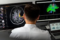Forscher sitzt vor zwei Bildschirmen und macht eine 