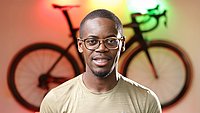 Portrait photo of Emmanuel Adjei, in the background an illuminated bicycle