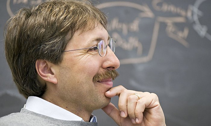 Professor Dirk Busch before a chalkboard.