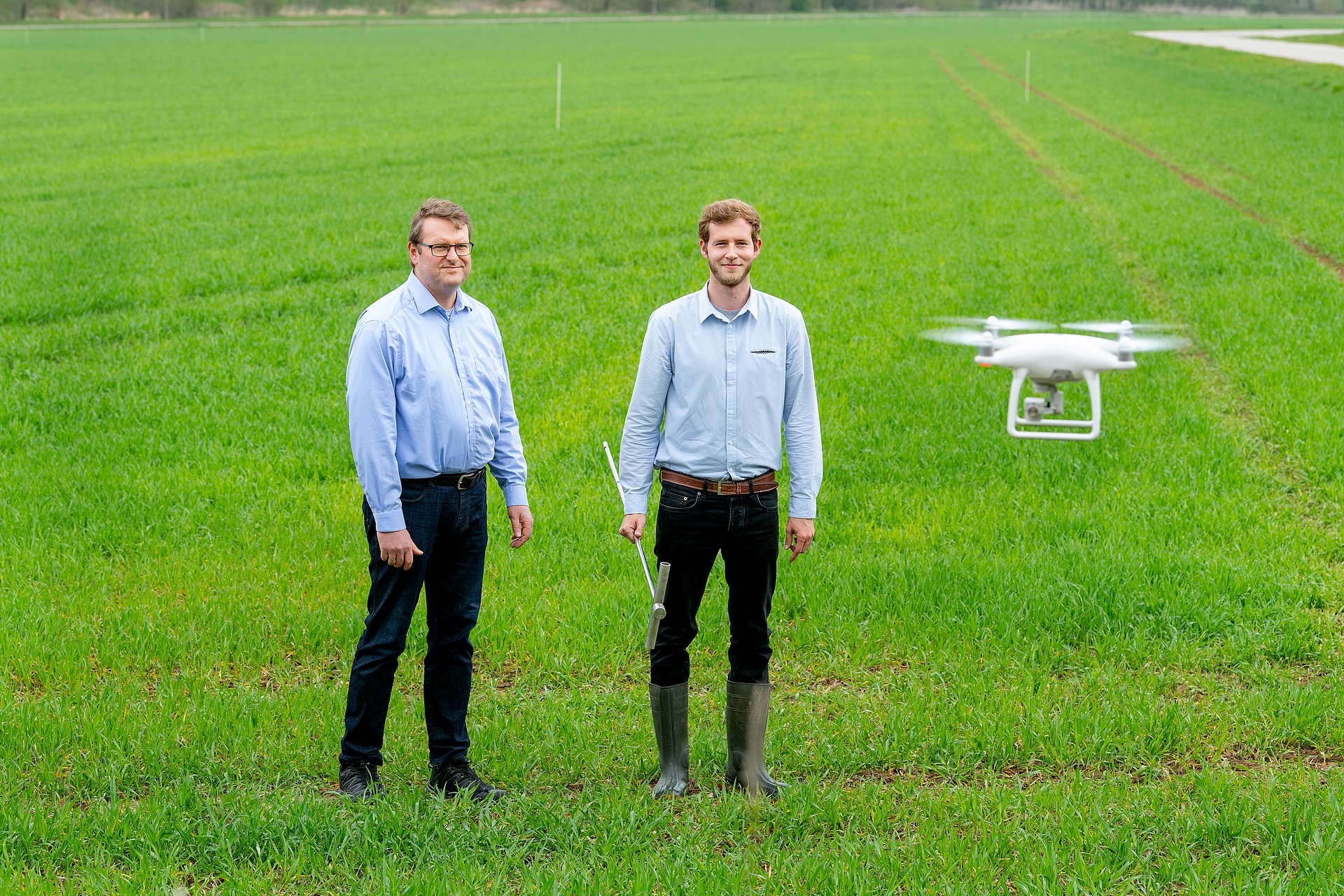 Prof. Heinz Bernhardt, Lehrstuhl für Agrarsystemtechnik, und sein Mitarbeiter Andreas Schweiger stehen auf dem Versuchsfeld mit Drohne.