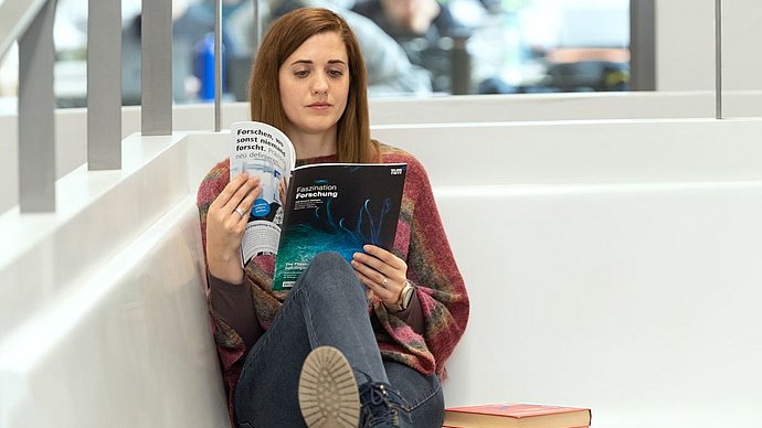 Eine Person liest in der Ausgabe 29 von „Faszination Forschung“.