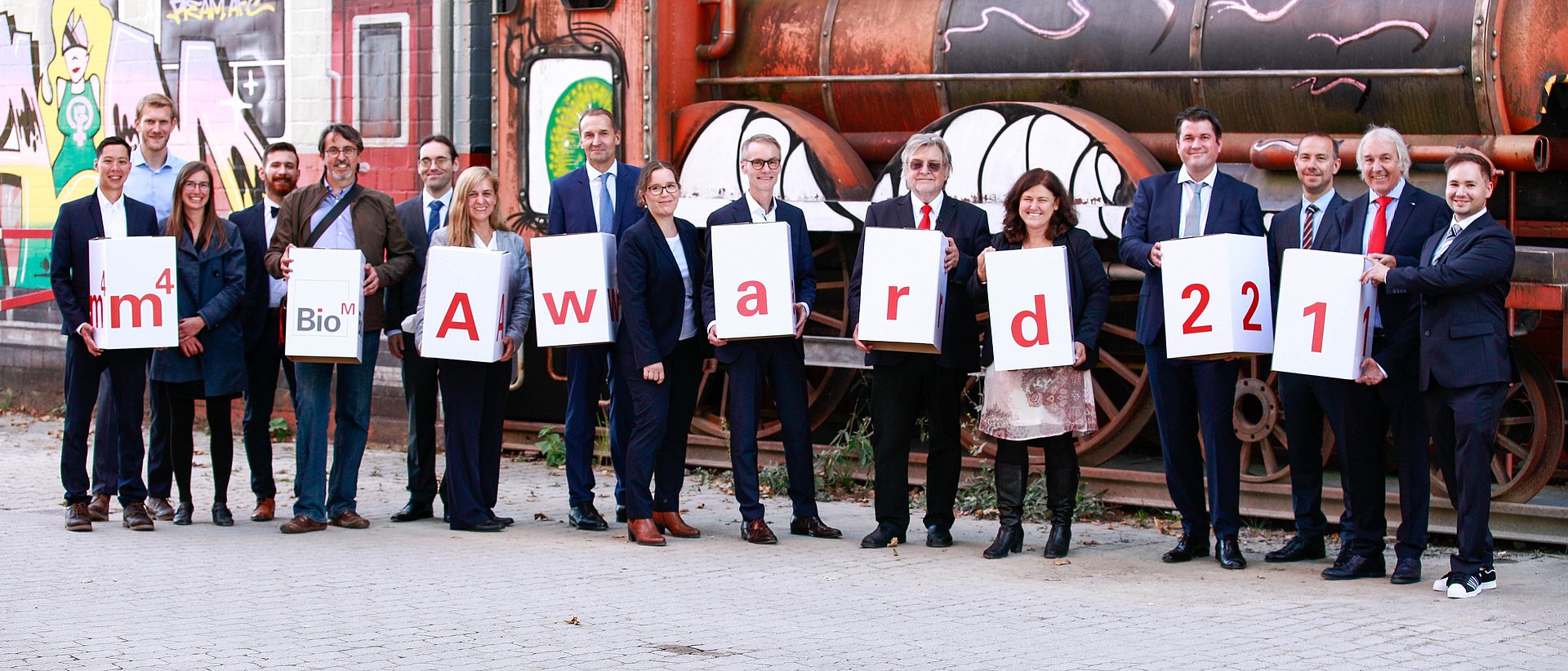 The winning teams of the m4 Award 2021 with Dr. Manfred Wolter (StMWi, 7th from right) and Prof. Horst Domdey (CEO of BioM, 6th from right).