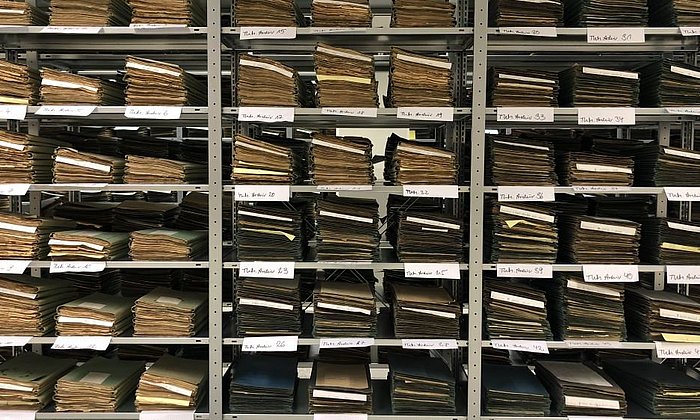 On the image a shelf with historical documents in the TUM Archive is shown.