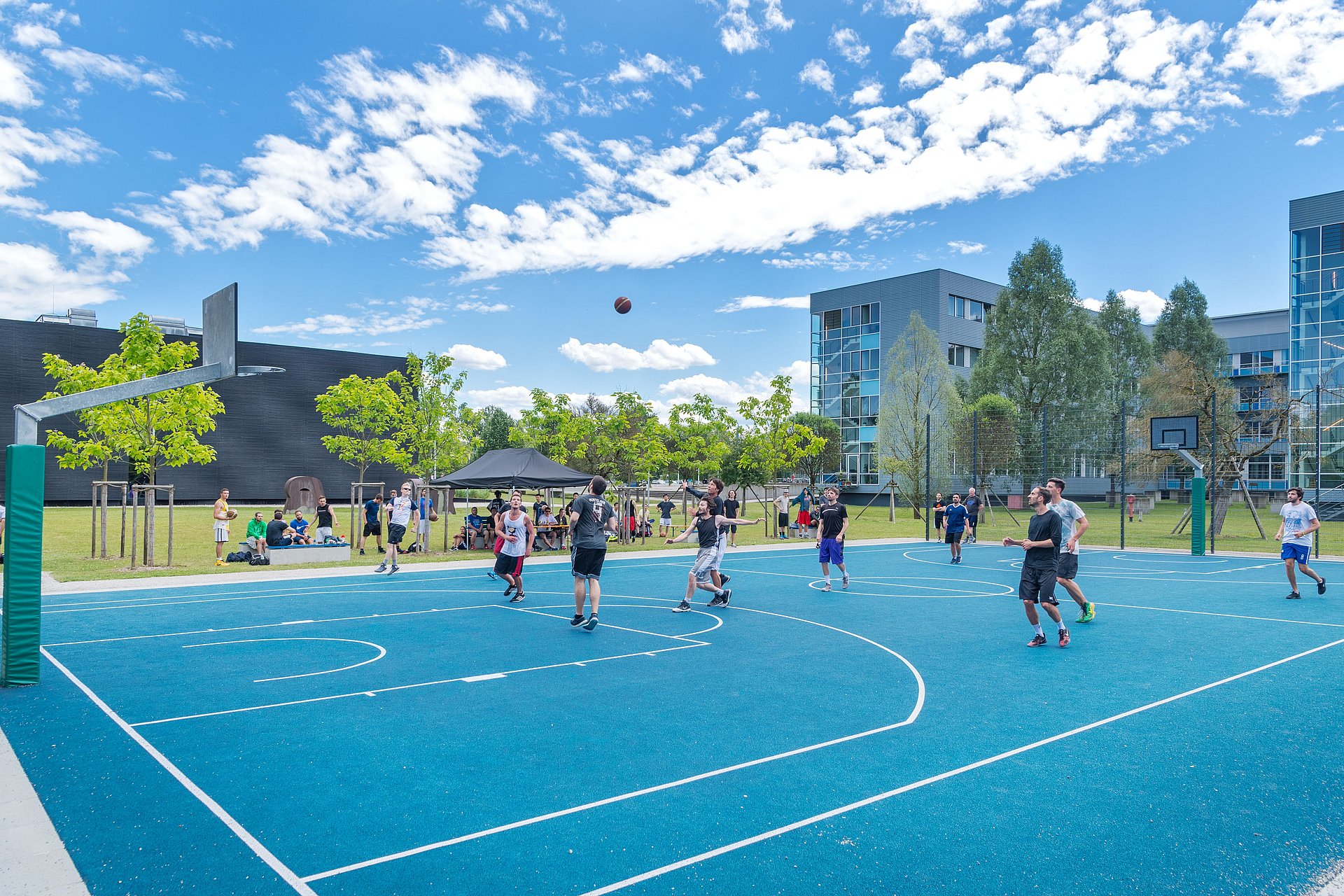 Students playing basketball on the court in the middle of the campus Garching