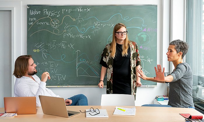 Prof. Dr. Laura Fabbietti (rechts) diskutiert mit Laura Šerkšnytė (Mitte) und Stephan Königstorfer über die Experimente zur Antihelium-3-Wechselwirkung.