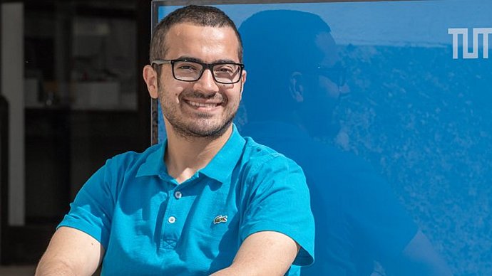 Hussein Al Ammawi in front of a blue cube