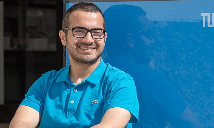 Hussein Al Ammawi in front of a blue cube