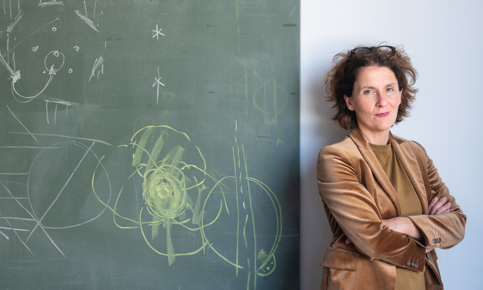 Prof. Elisa Resconi next to an inscribed plaque, with her arms crossed