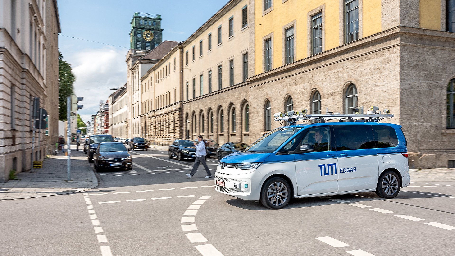 A minibus with roof attachments and sensor technology for autonomous driving drives through Munich.