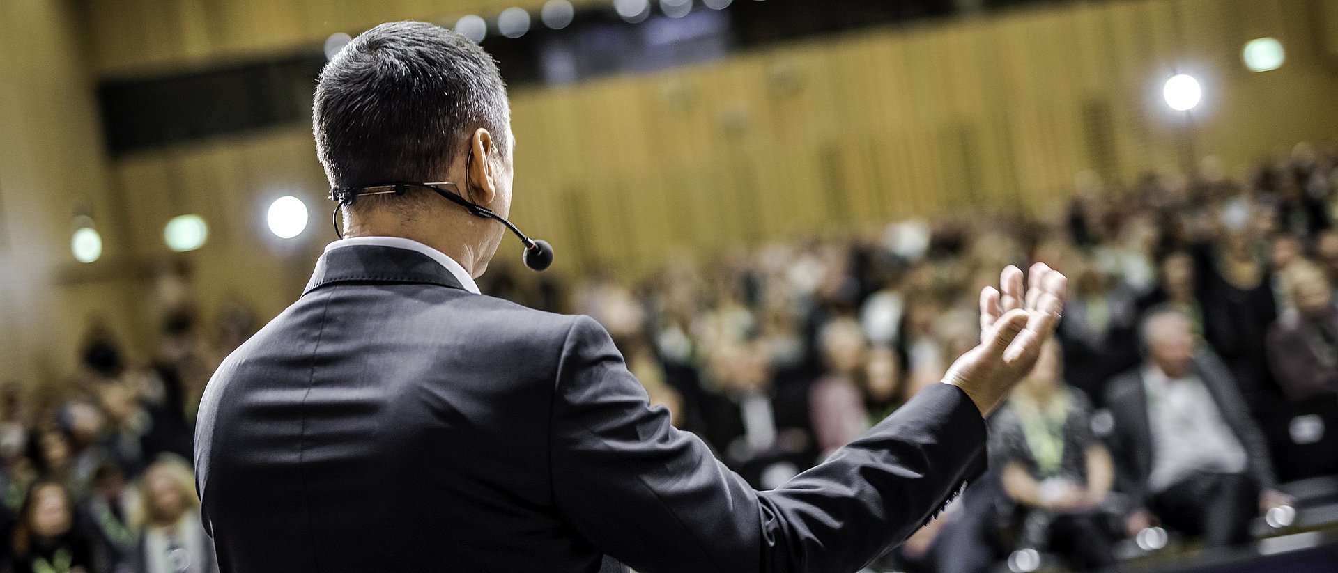 Man speaks in front of an audience with a headset