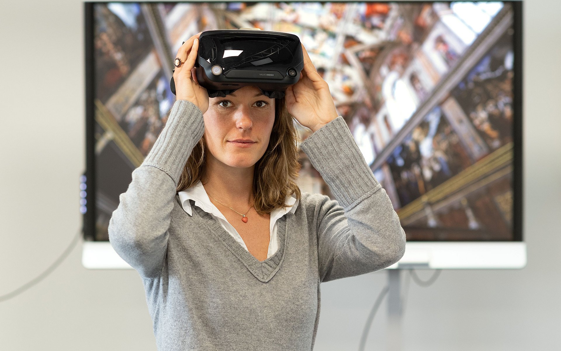 Vorlesung mit VR-Brille Eine Frau mit einer VR-Brille steht vor einem Bildschirm.