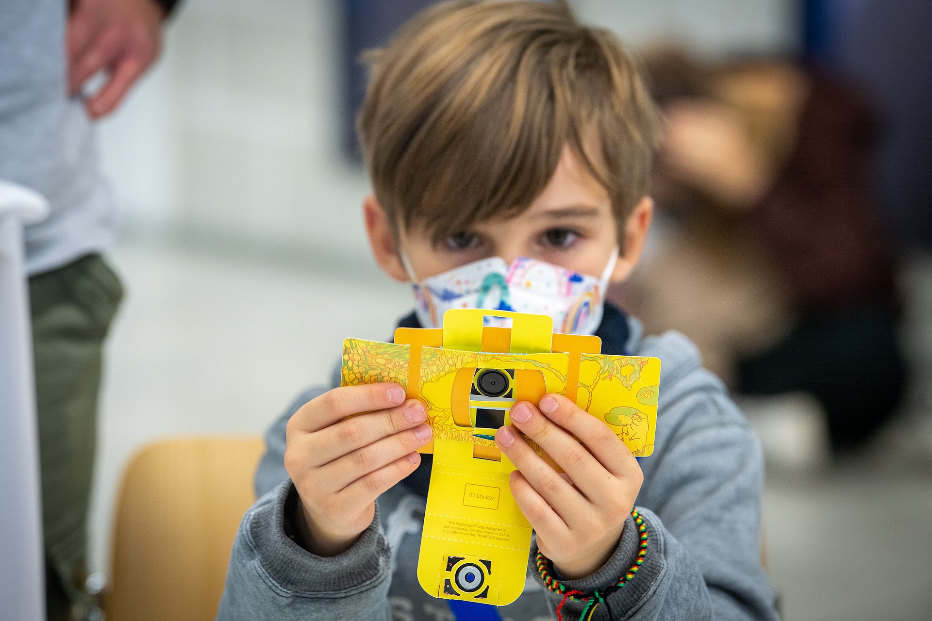 A child shows the cardboard microscope he made.