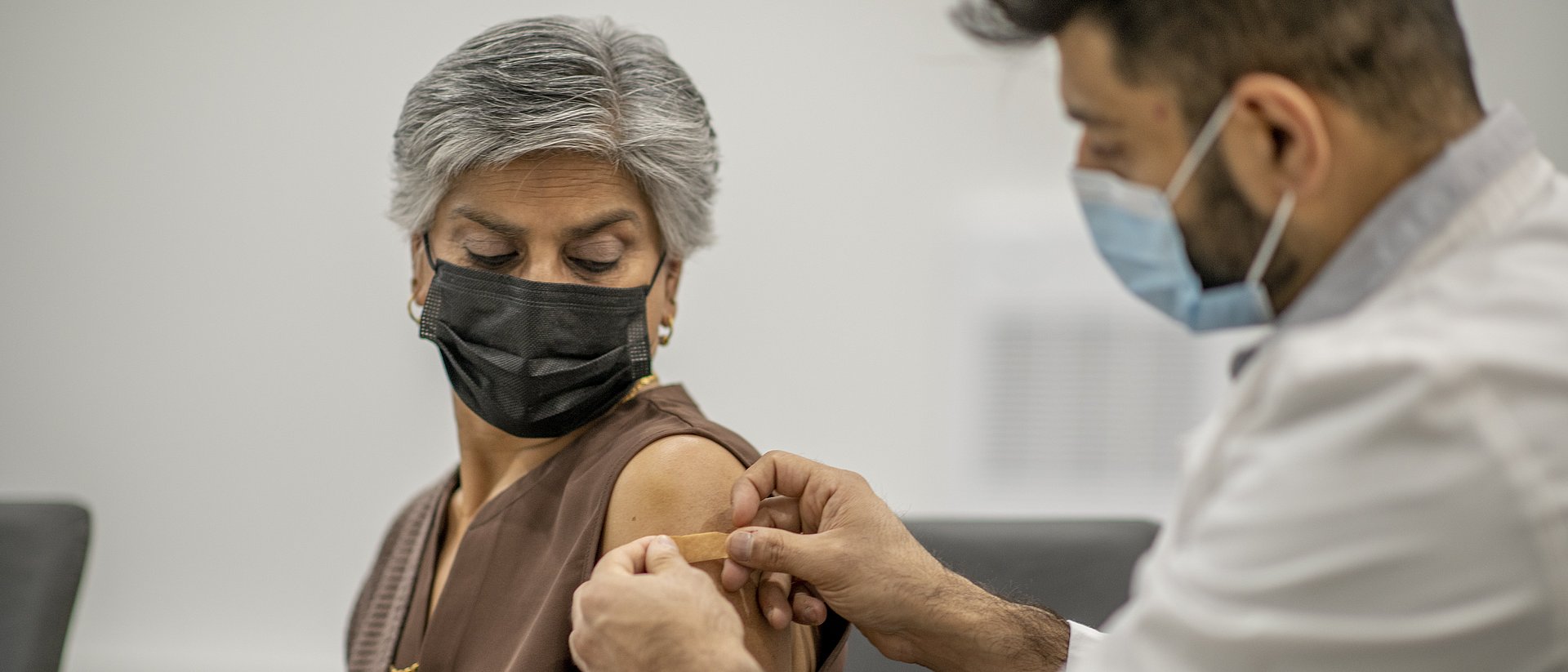 Eine Frau lässt sich von einem Mediziner impfen.