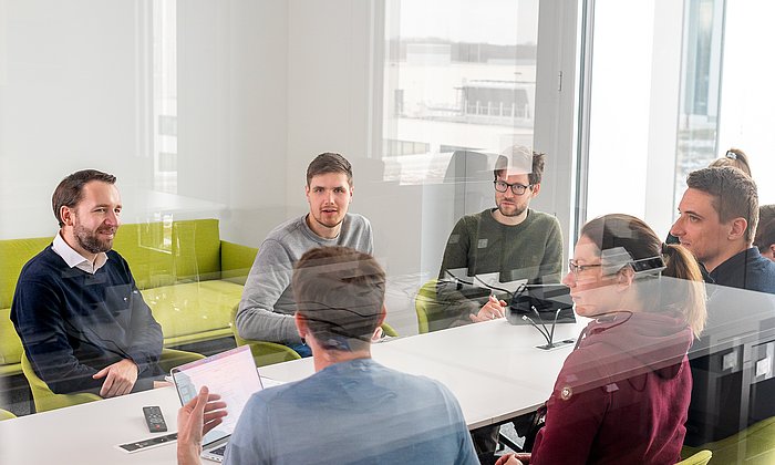 Gruppe von Menschen an einem Konferenztisch, darunter Prof. Günnemann, der Sprecher der relAI