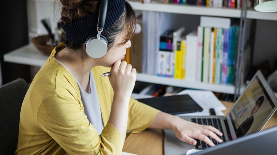 Frau mit Kopfhörern an Laptop