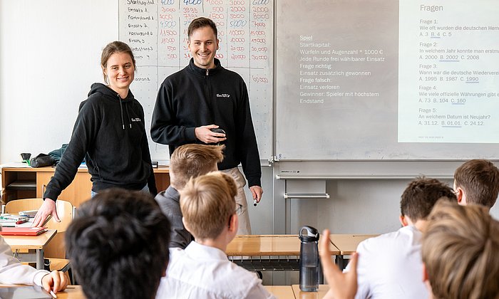 Studierende bringen Schüler:innen in dem Workshop "Because we care" einen verantwortungsvollen Umgang mit Geld bei